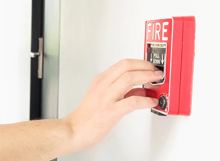 Imagem de uma pessoa acionando um ponto de chamada de alarme de incêndio